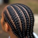 Close-up of a scalp with neatly woven cornrow braids in parallel rows.
